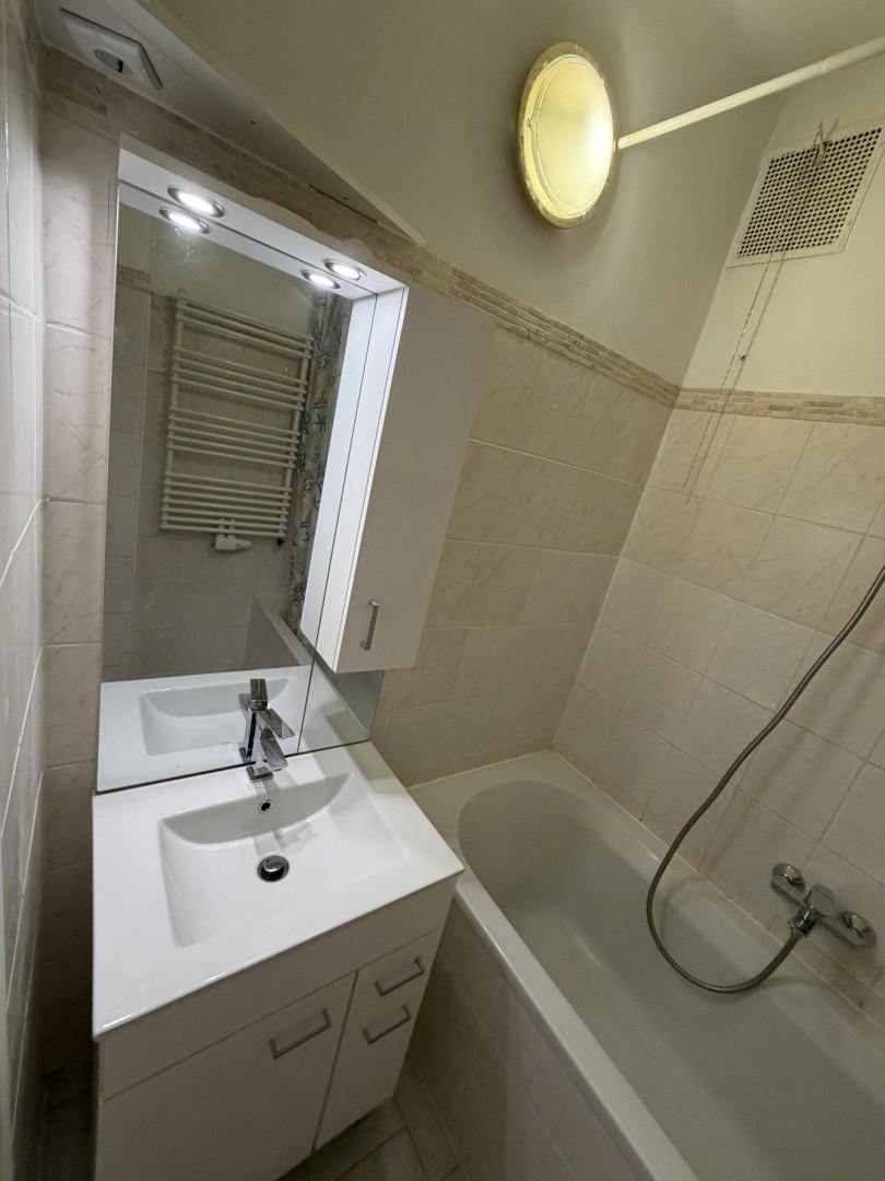 Helles Badezimmer mit Waschbecken, Spiegelschrank, Badewanne und beheiztem Handtuchhalter.