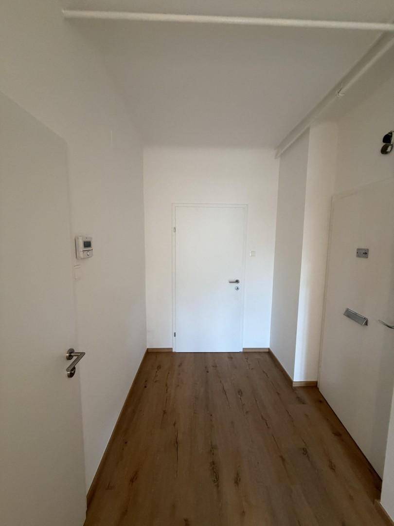 Langer, heller Flur mit Holzboden und mehreren Türen, der die Wohnbereiche erschließt.