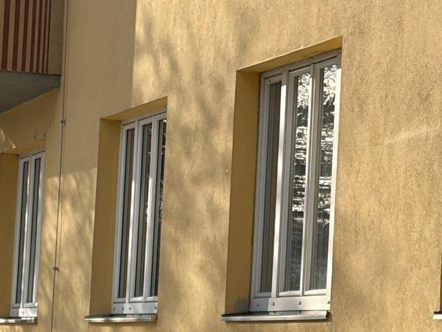 Fassade eines Gebäudes mit beigefarbenem Putz und hohen Fenstern.