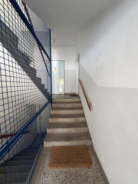 Treppenhaus mit Gittergeländer und Terrazzoboden in einem Mehrfamilienhaus.