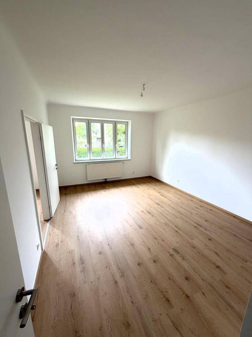 Lichtdurchflutetes Wohnzimmer mit Holzboden und weiß gestrichenen Wänden.