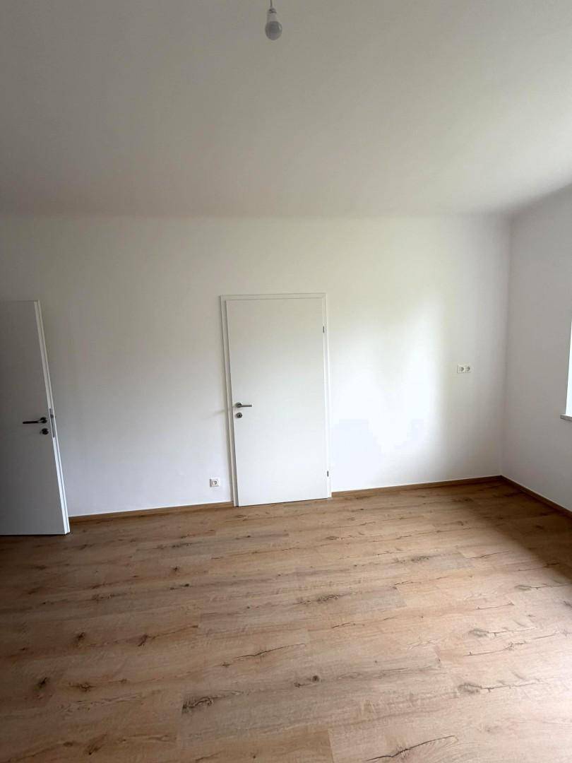 Leerer Raum mit hellem Holzboden und weißen Wänden, bereit zur individuellen Gestaltung.