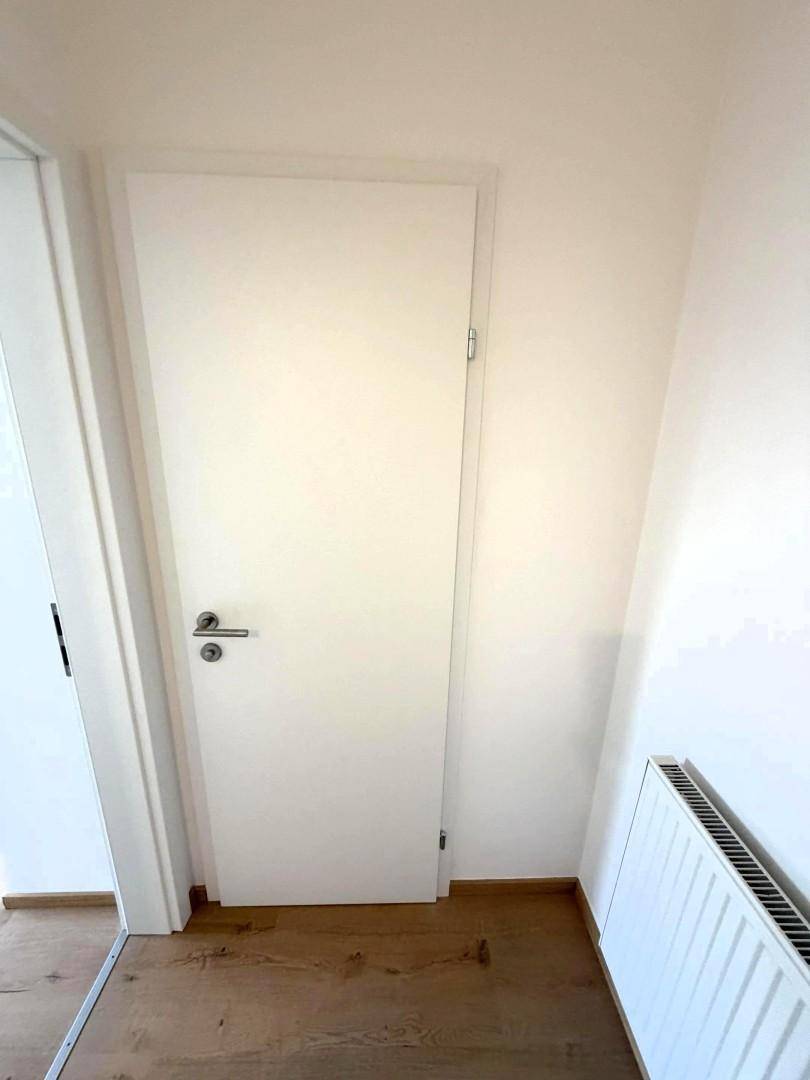 Heller Flur mit weißer Tür und Holzboden, der zu weiteren Räumen führt.