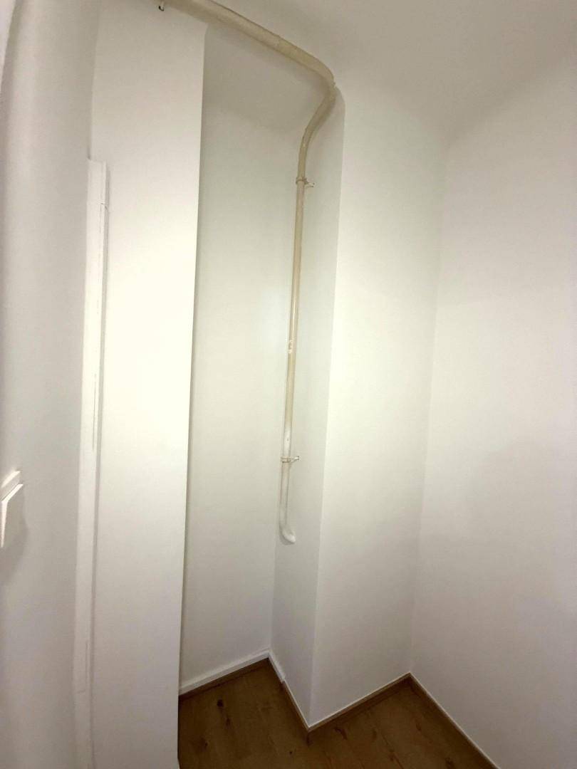 Kleiner Abstellraum oder Nische mit Holzboden und sichtbaren Leitungen.