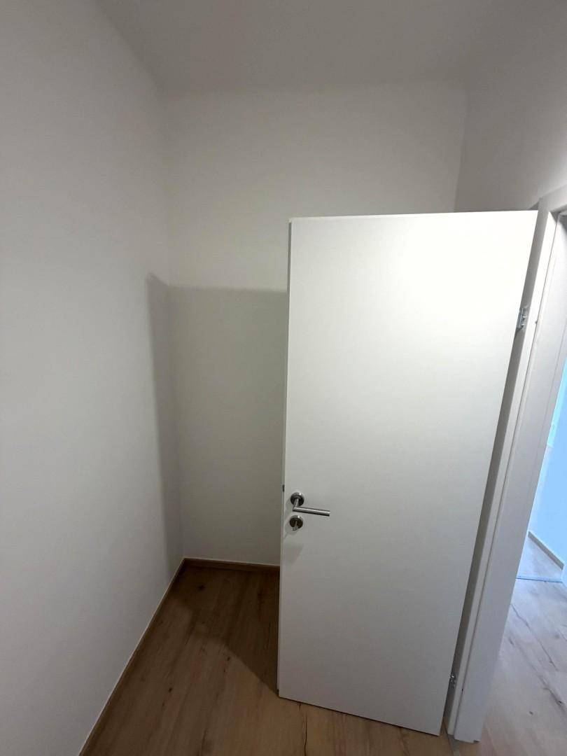 Praktischer Abstellraum mit Tür und Holzboden für zusätzlichen Stauraum.