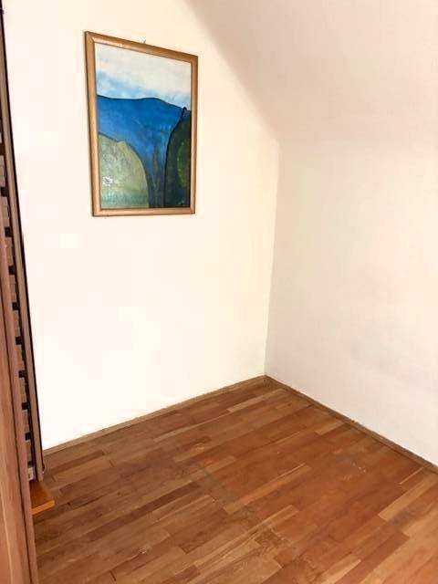 Leerer Raum im Dachgeschoss mit schräger Decke und Holzboden.