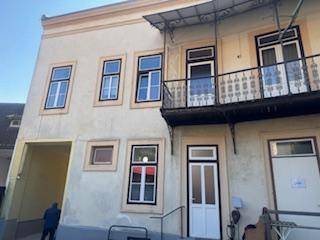 Fassade eines älteren Gebäudes mit mehreren Fenstern und einem Balkon mit schmiedeeisernem Geländer.