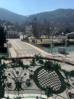 Panoramablick auf eine Brücke, einen Fluss und die umliegenden Berge von einem Balkon.