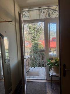 Heller Flur mit Zugang zu einem kleinen Balkon und Blick ins Grüne.