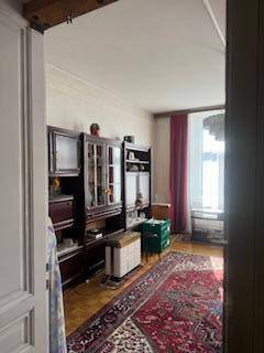 Wohnzimmer mit Holzboden, Teppich, klassischen Möbeln und einem großen Fenster mit rotem Vorhang.