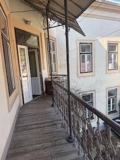 Langer, schmaler Holzbalkon mit schmiedeeisernem Geländer und Blick auf die Gebäudefassade.