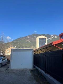 Einzelgarage vor einer Bergkulisse mit klarem blauen Himmel.