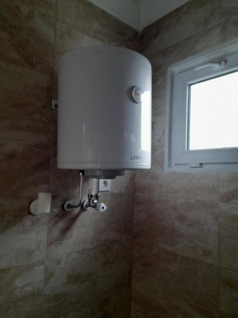 Detailaufnahme eines Warmwasserboilers im Badezimmer neben einem Fenster.