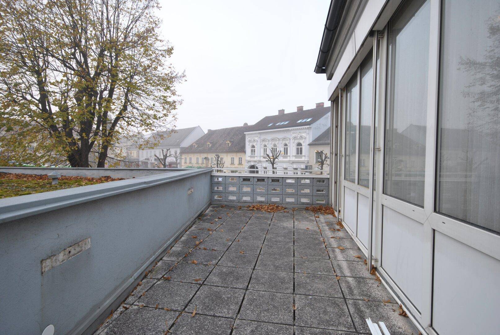 Geräumige Außenterrasse mit Blick auf die umliegenden Gebäude und viel Potenzial für Gestaltung.