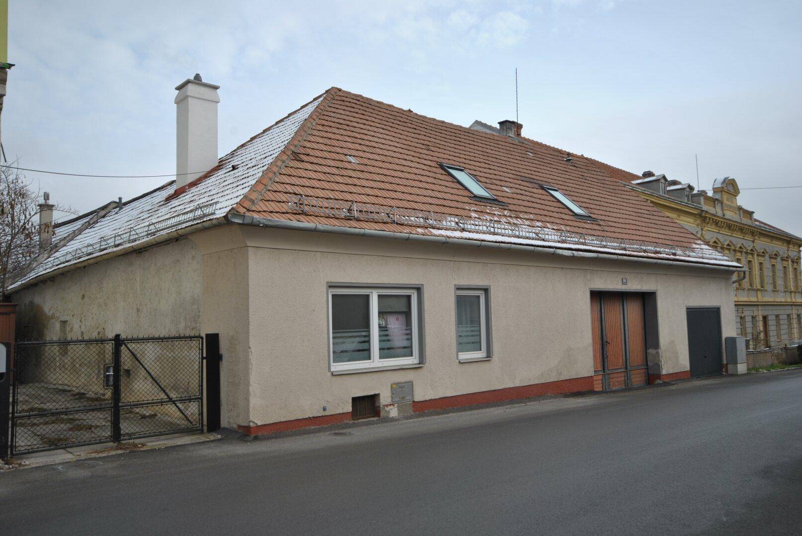 Gebäudeansicht von der Straße mit Ziegeldach, Dachfenstern und leichtem Schneebedeckung.