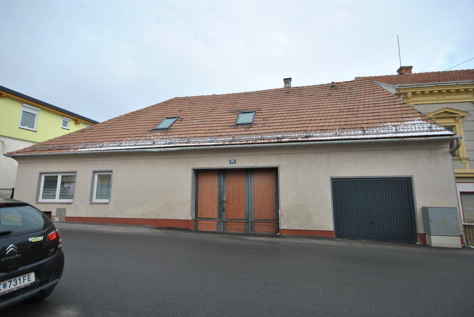 Ansicht des Gebäudes von der Straße mit Ziegeldach und einem schwarzen Auto davor.