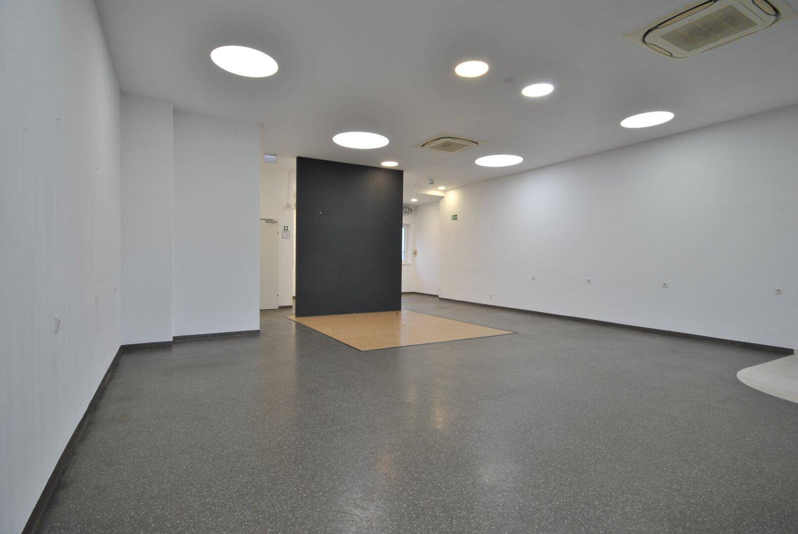 Geräumiger Innenbereich mit weiß gestrichenen Wänden, dunklem Boden und einer modernen schwarzen Akzentwand.