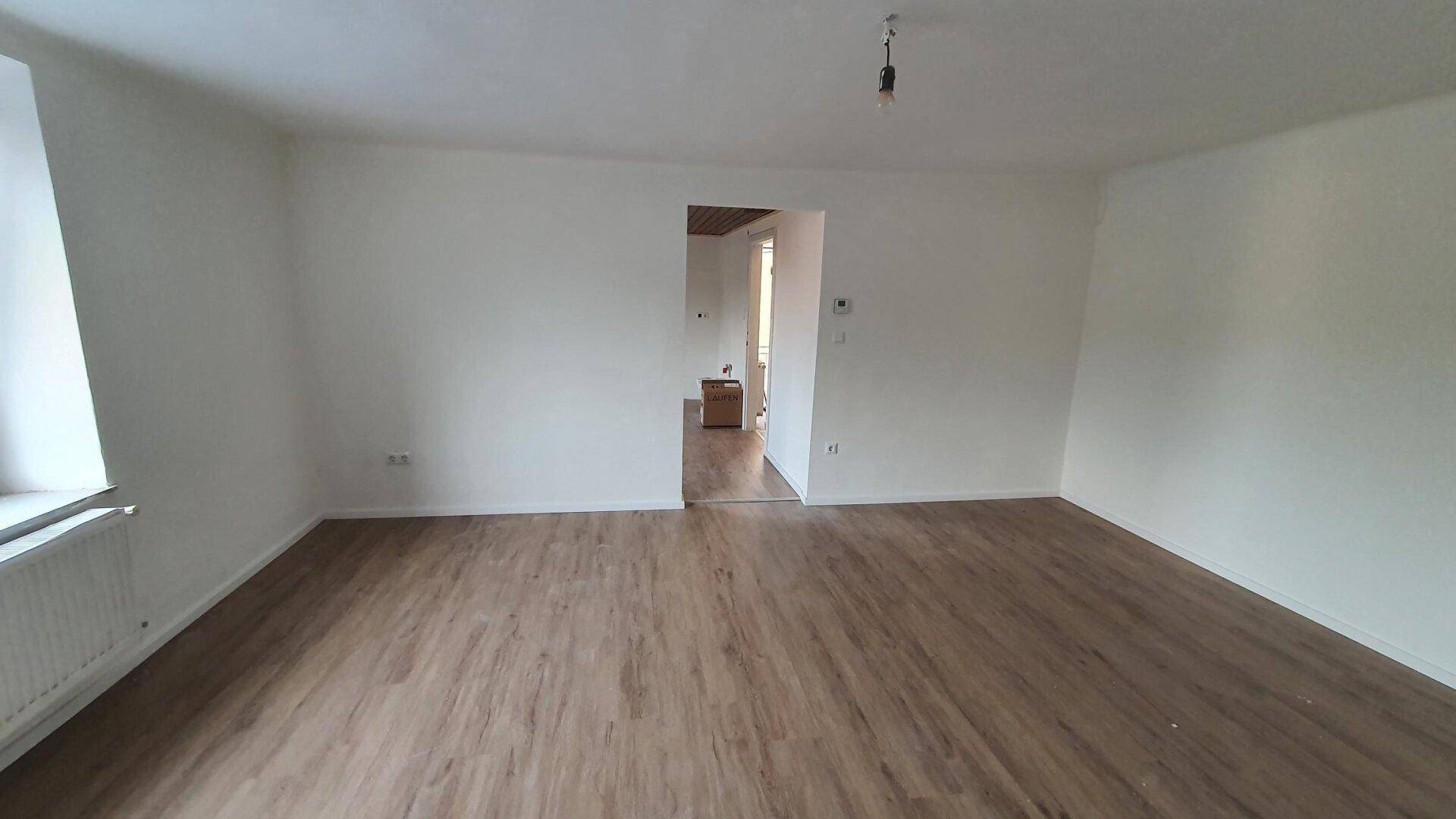 Geräumiger Innenraum mit Laminatboden und weiß gestrichenen Wänden, bereit zum Einzug.