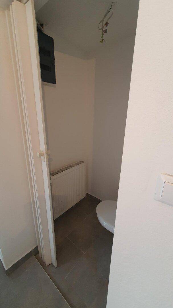 Kleines Gäste-WC mit Fliesenboden, Toilette und Heizkörper.