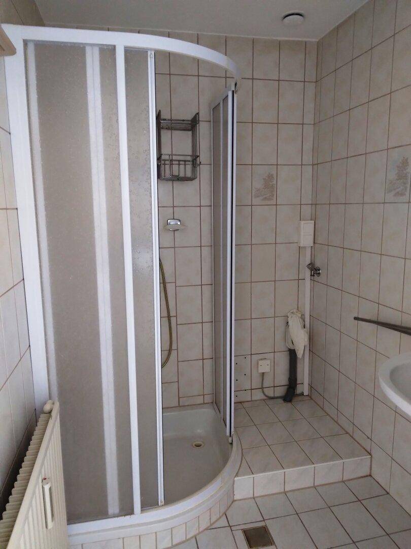 Badezimmer mit Duschkabine, gefliesten Wänden und Boden in hellem Beige.