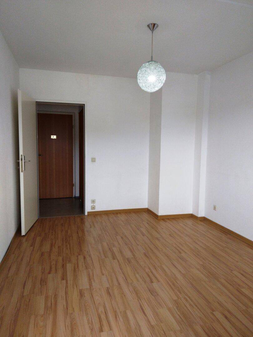 Heller Raum mit Laminatboden und moderner Deckenleuchte, ideal für Schlaf- oder Wohnbereich.