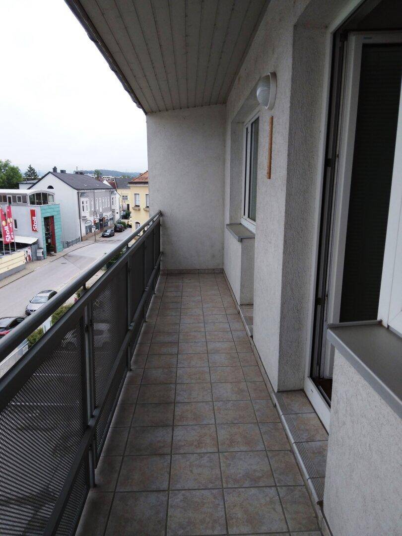 Schmaler Balkon mit Fliesenboden und Metallgeländer, bietet Blick auf die Straße.