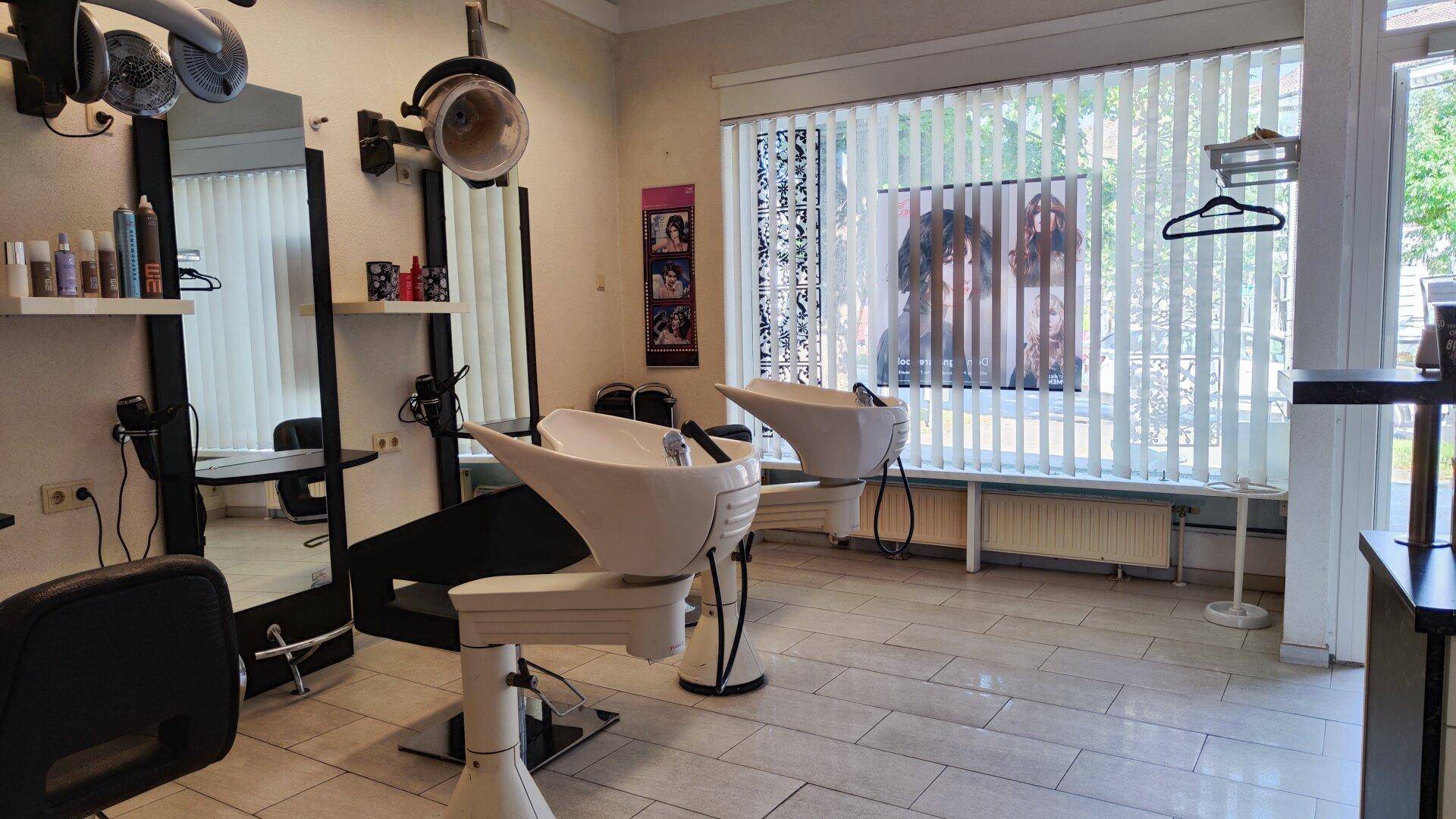 Friseursalon mit Waschbecken, Spiegeln und Stühlen, ausgestattet für Kundenbedienung.