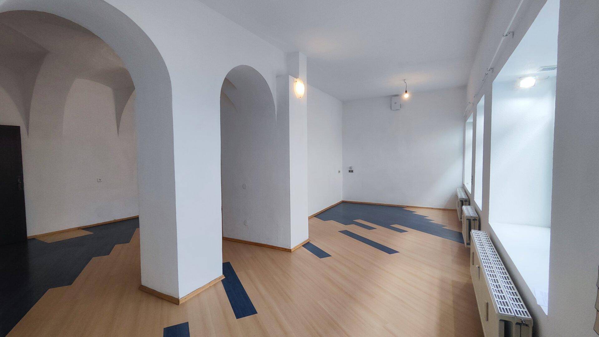 Geräumiger Geschäftsraum mit hohen Decken, eleganten Rundbögen und einem einzigartigen Bodenmuster.