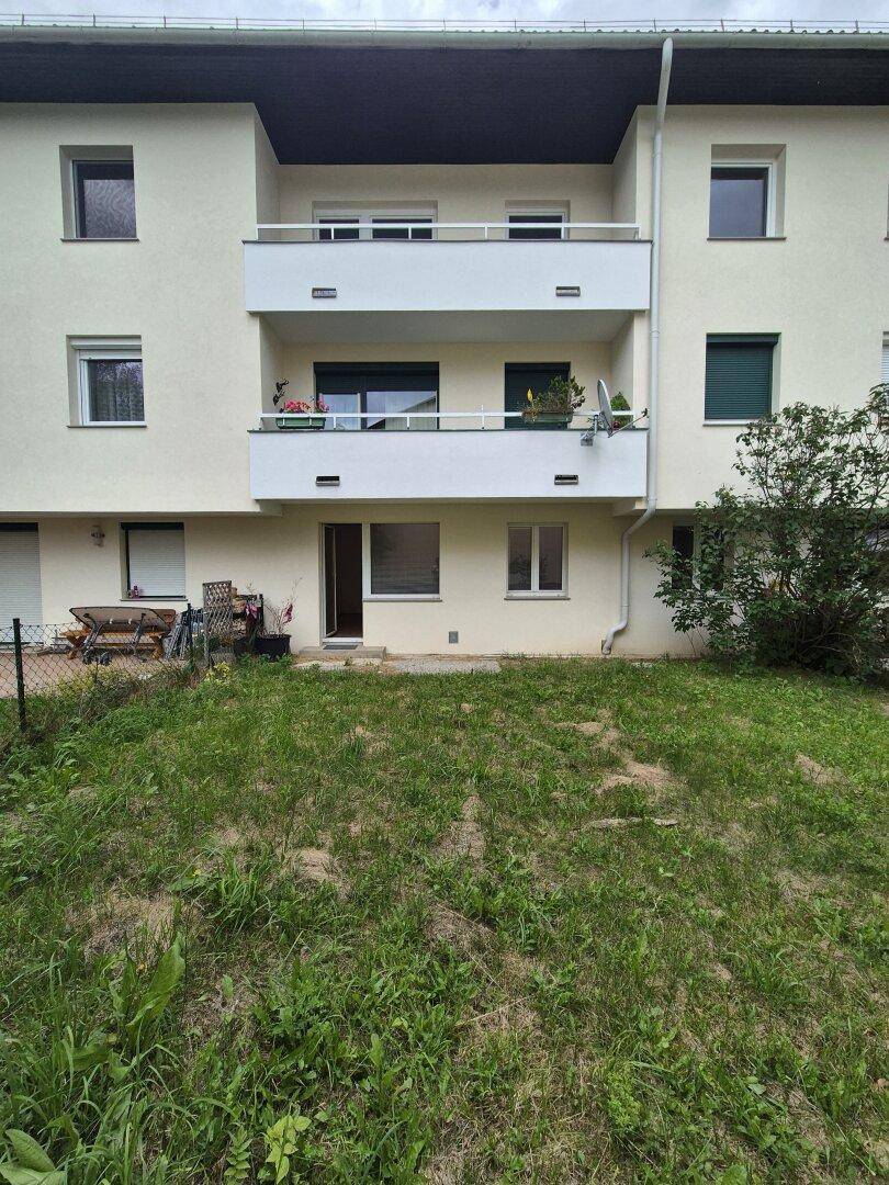 Außenansicht eines Mehrfamilienhauses mit Balkonen und einem Rasenbereich im Vordergrund.