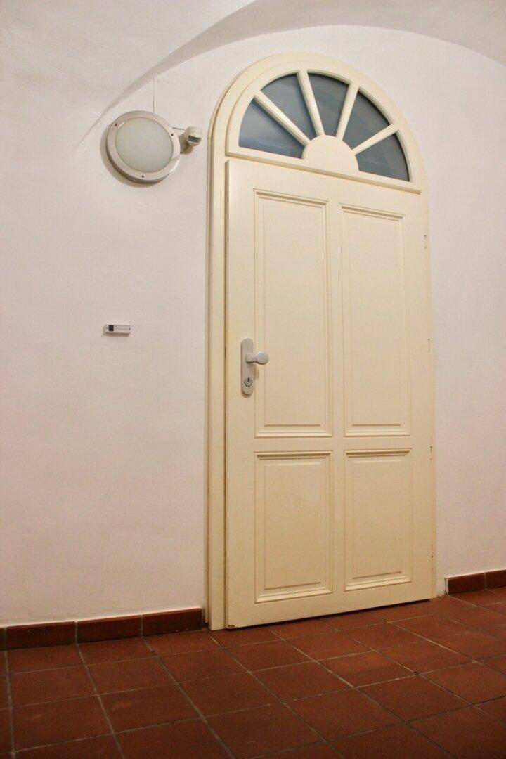 Eingangsbereich mit traditioneller Holztür und Terrakottafliesen, strahlt historischen Charme aus.