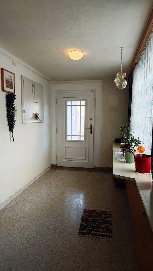 Eingangsbereich mit heller Tür, Fenster und Ablagefläche, freundlich gestaltet.