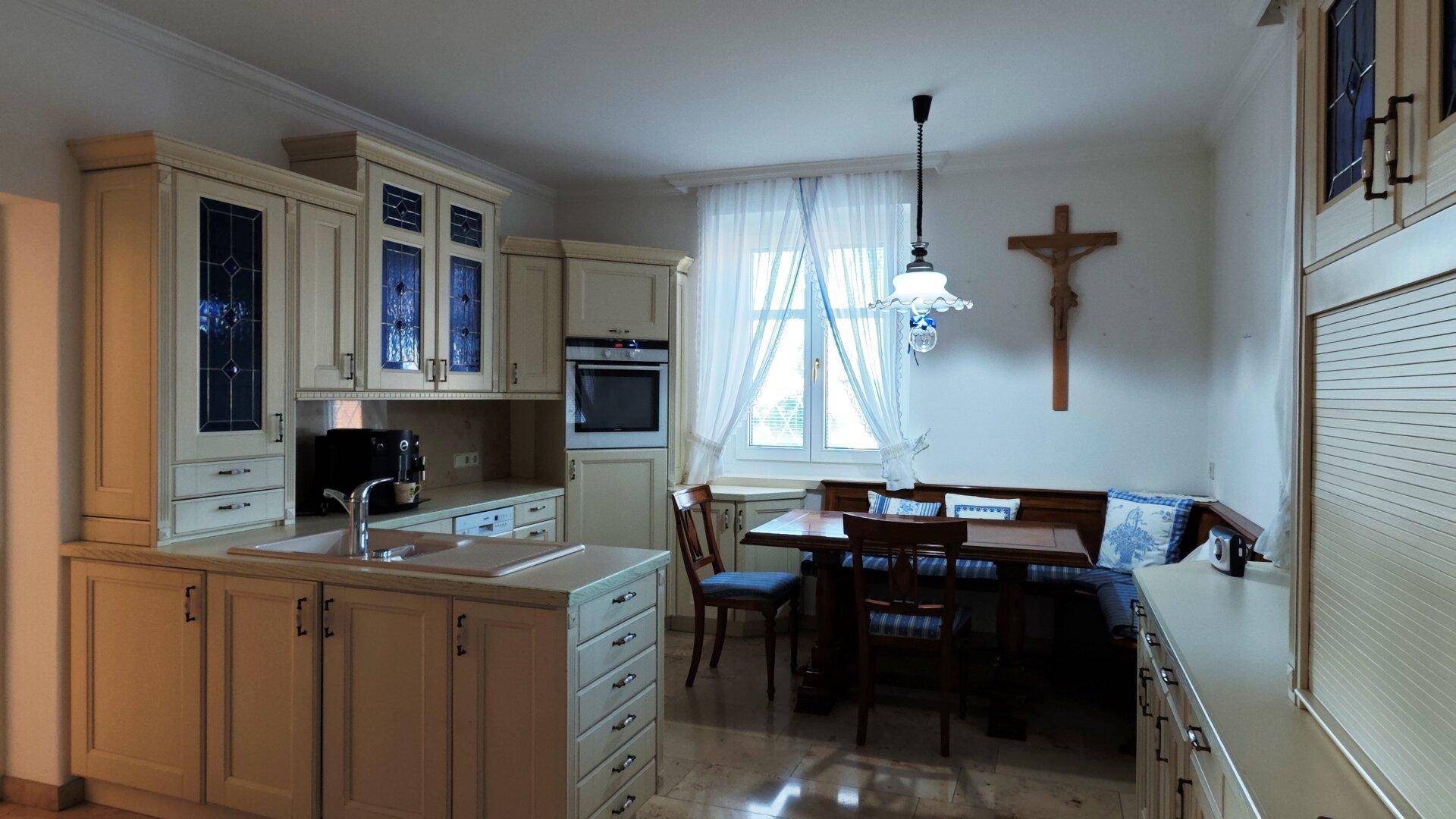 Gemütliche Wohnküche mit Essbereich, Holztisch und traditionellen Elementen wie einem Kruzifix.