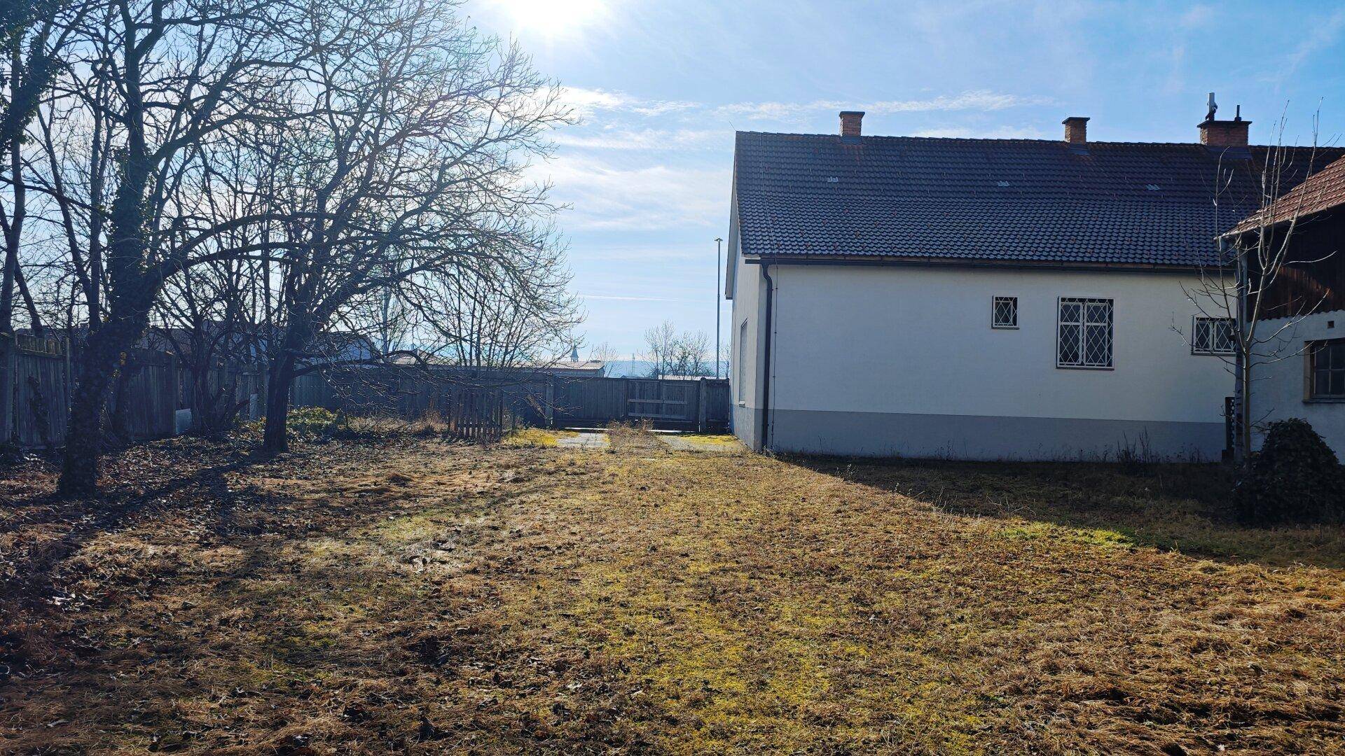 Großer Gartenbereich hinter dem Haus mit Rasenfläche und Bäumen.