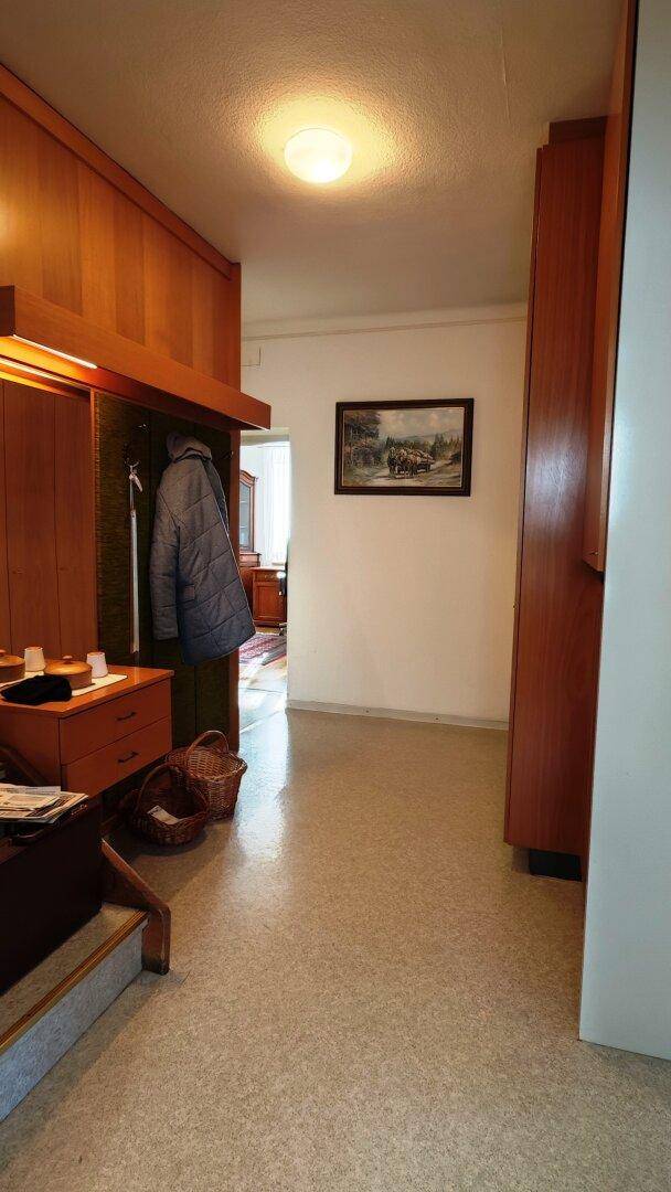 Heller Flur mit Holzvertäfelung, Garderobe und Blick in angrenzende Räume.