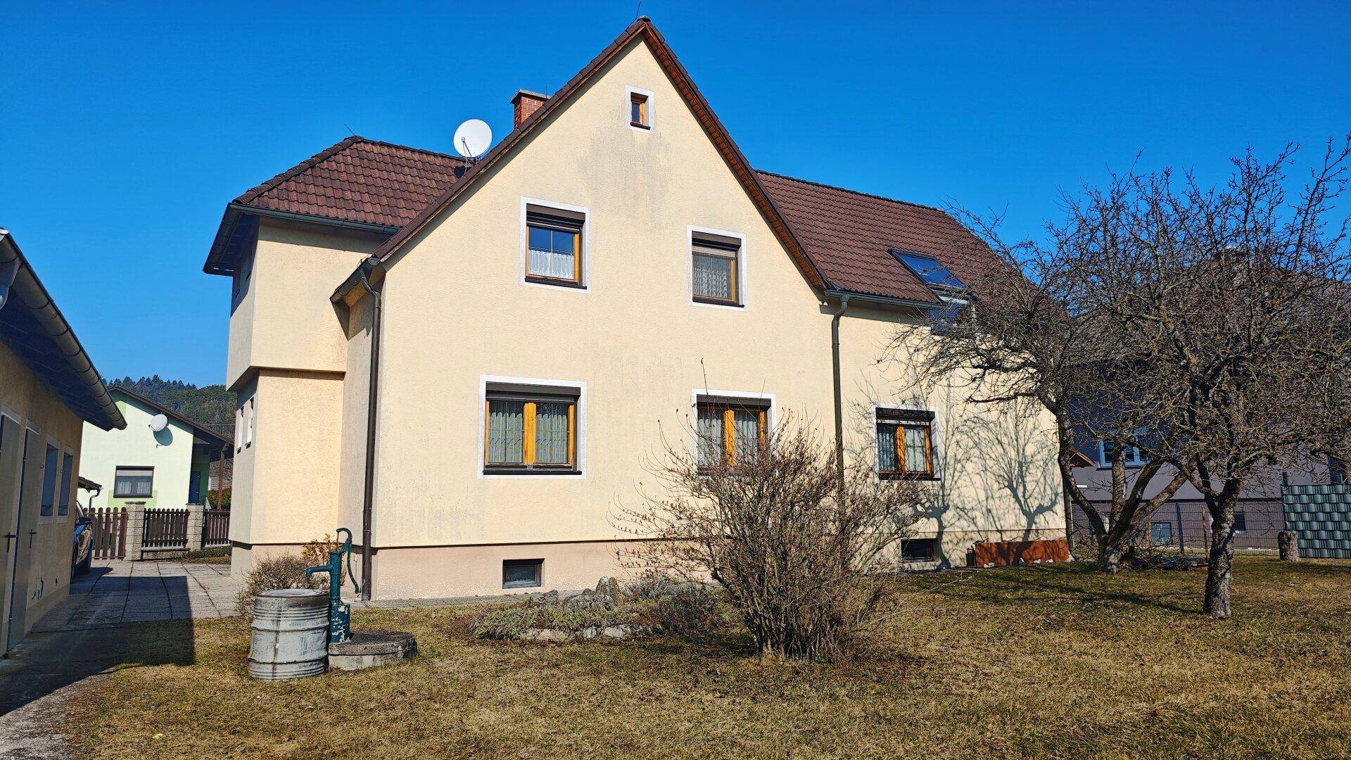 Rückansicht des Einfamilienhauses mit Garten und traditionellem Satteldach.