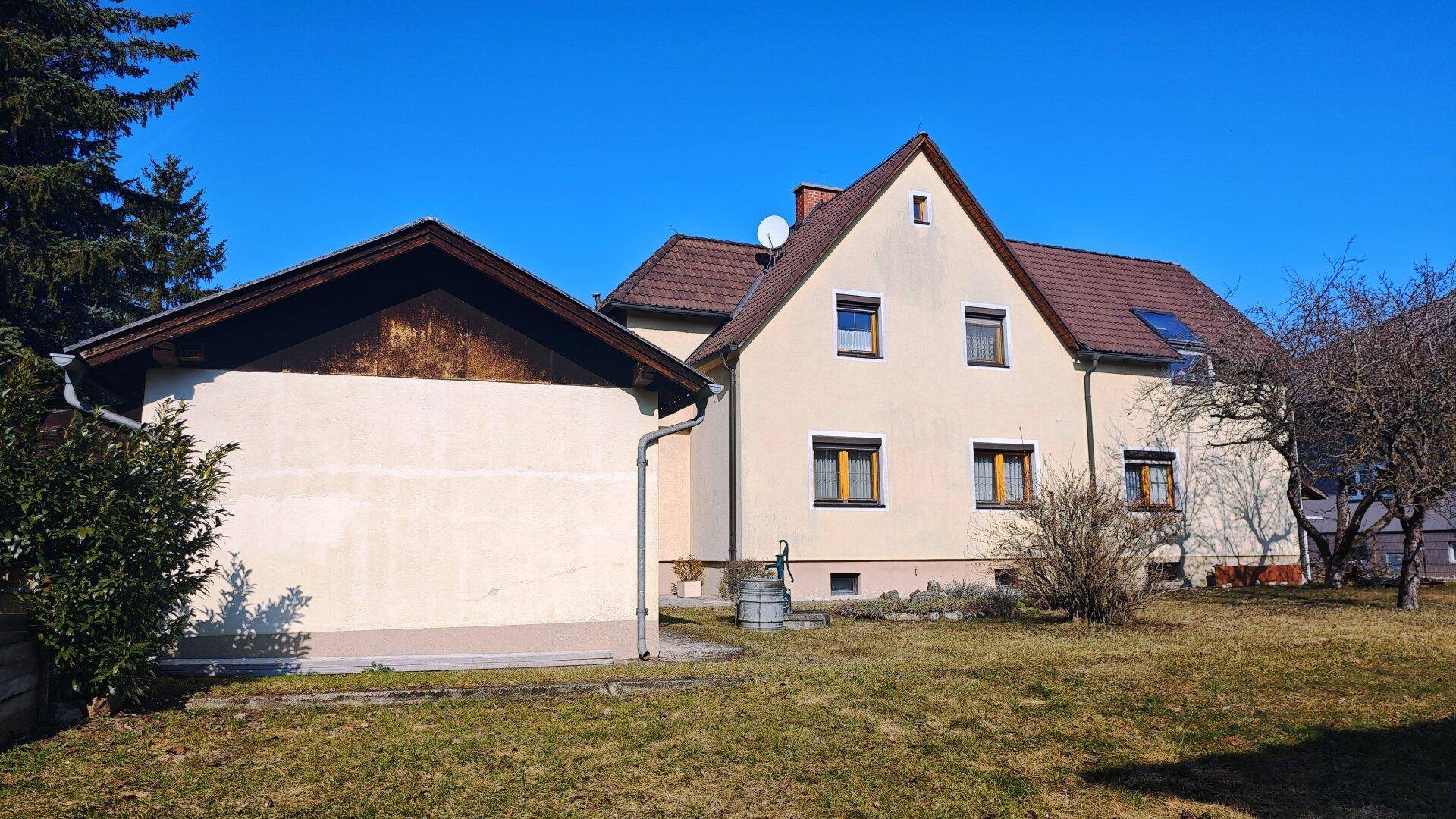 Einfamilienhaus mit angrenzendem Nebengebäude und weitläufigem Gartenbereich.