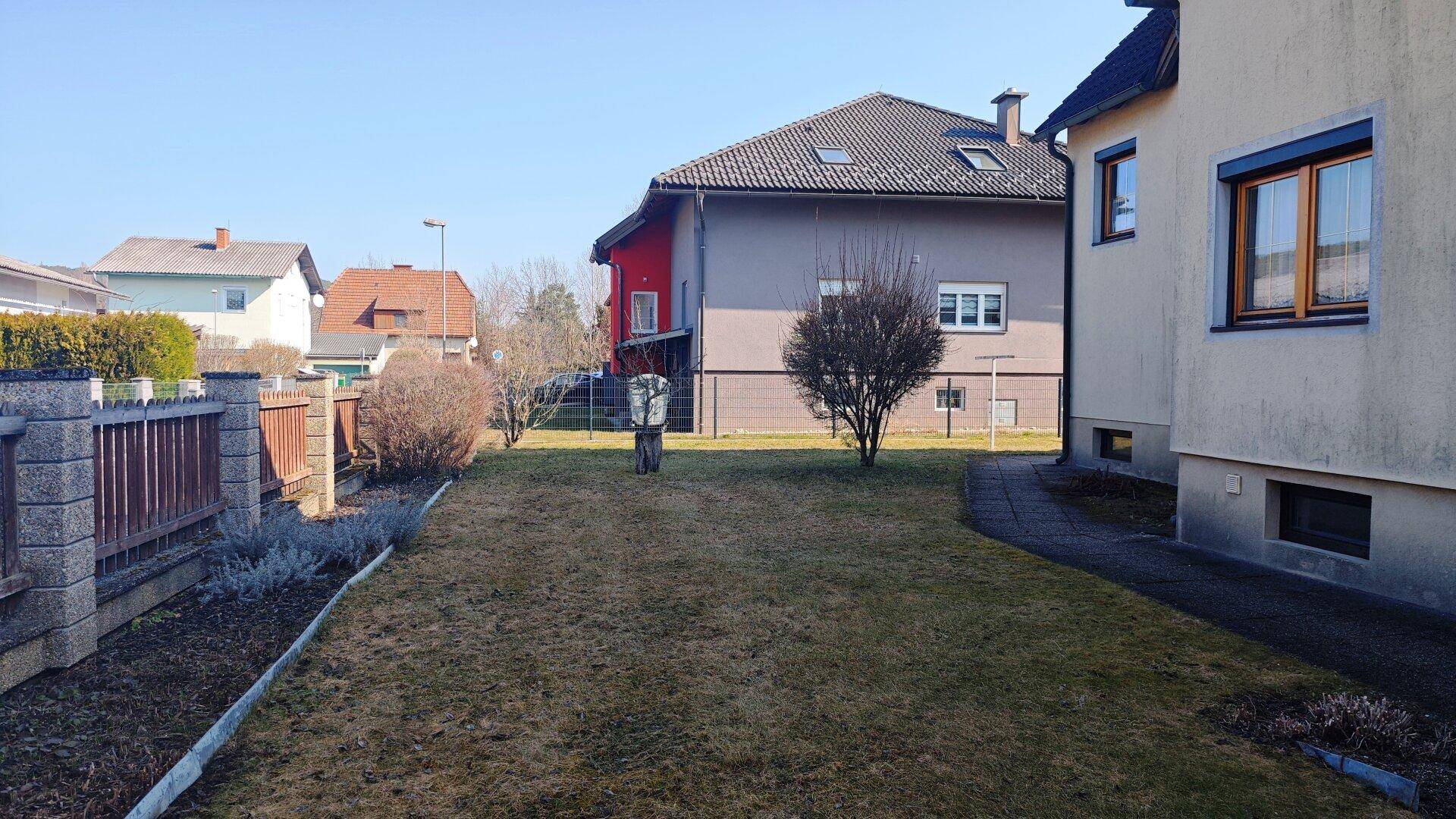 Gepflegter Gartenbereich mit Rasen und Blick auf die umliegenden Wohnhäuser.