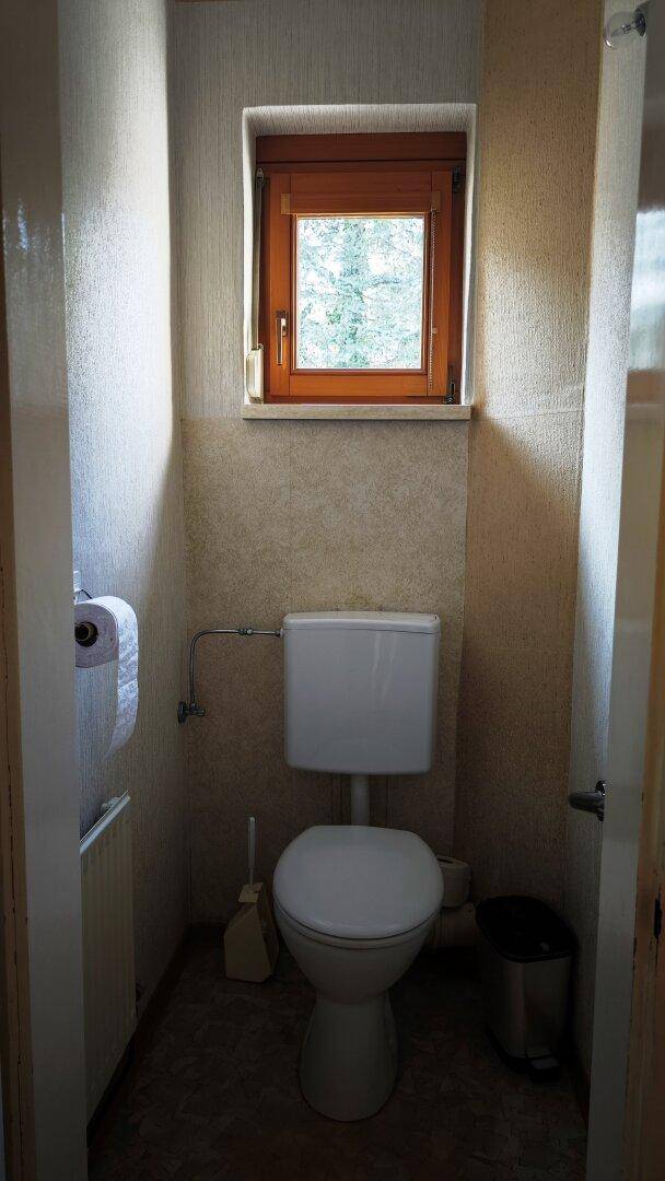Separate Toilette mit Fenster, Heizkörper und einfacher, funktionaler Ausstattung.