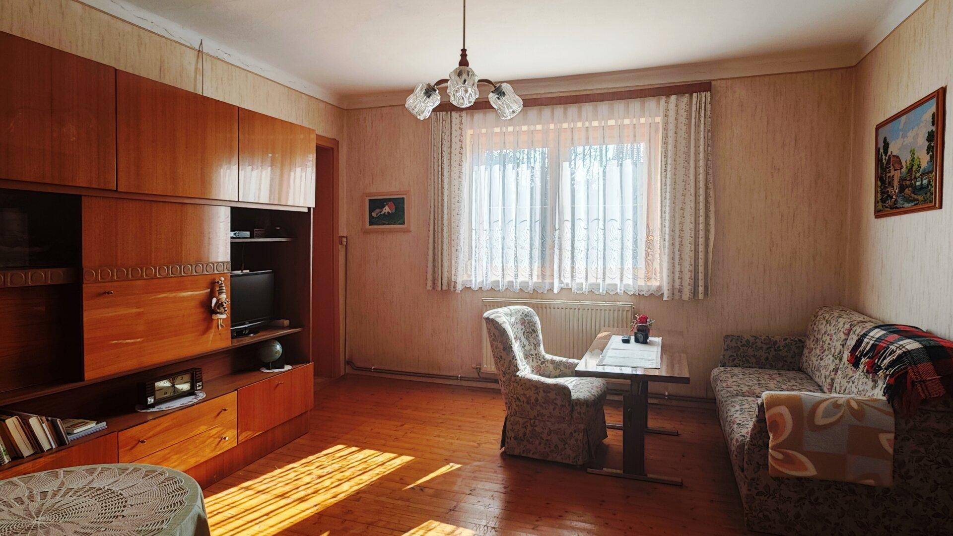 Wohnzimmer mit Holzparkett, traditionellen Möbeln und großem Fenster für viel Licht.