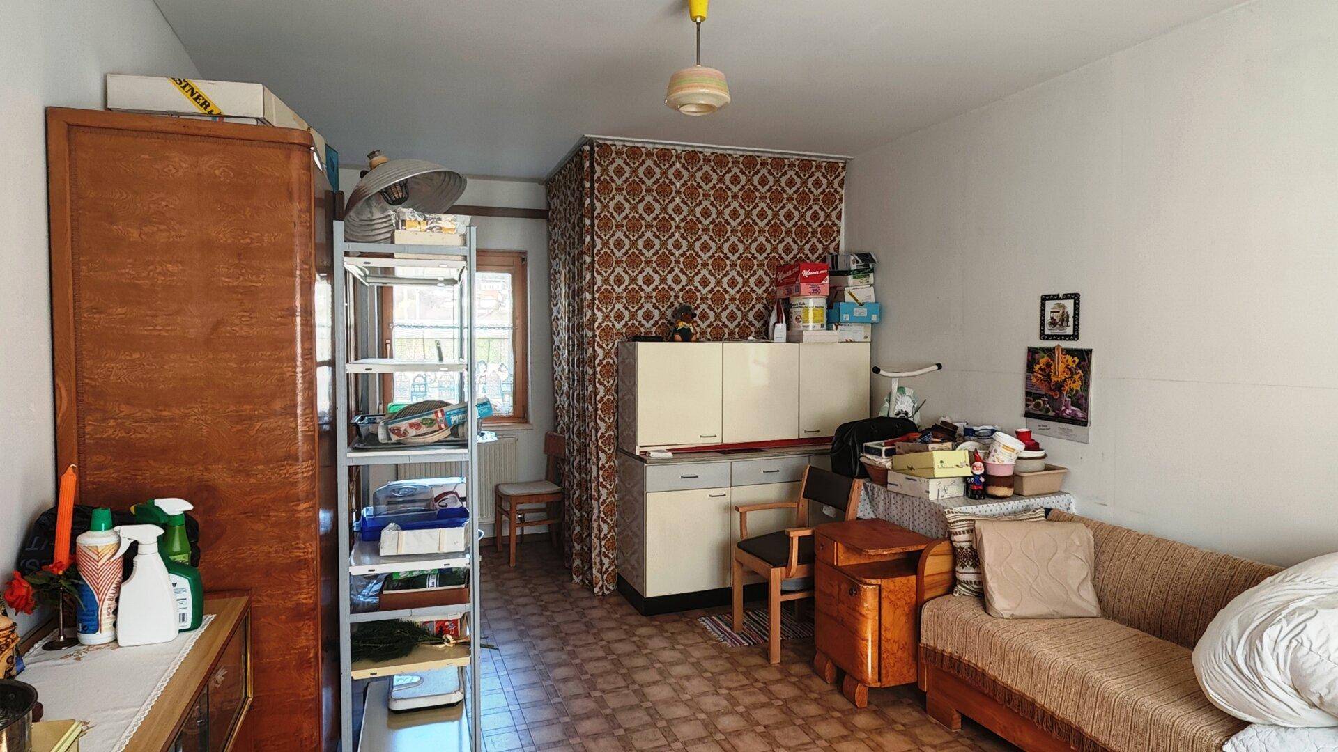 Mehrzweckraum mit kleiner Küchenzeile, Sofa und Stauraum, funktional eingerichtet.