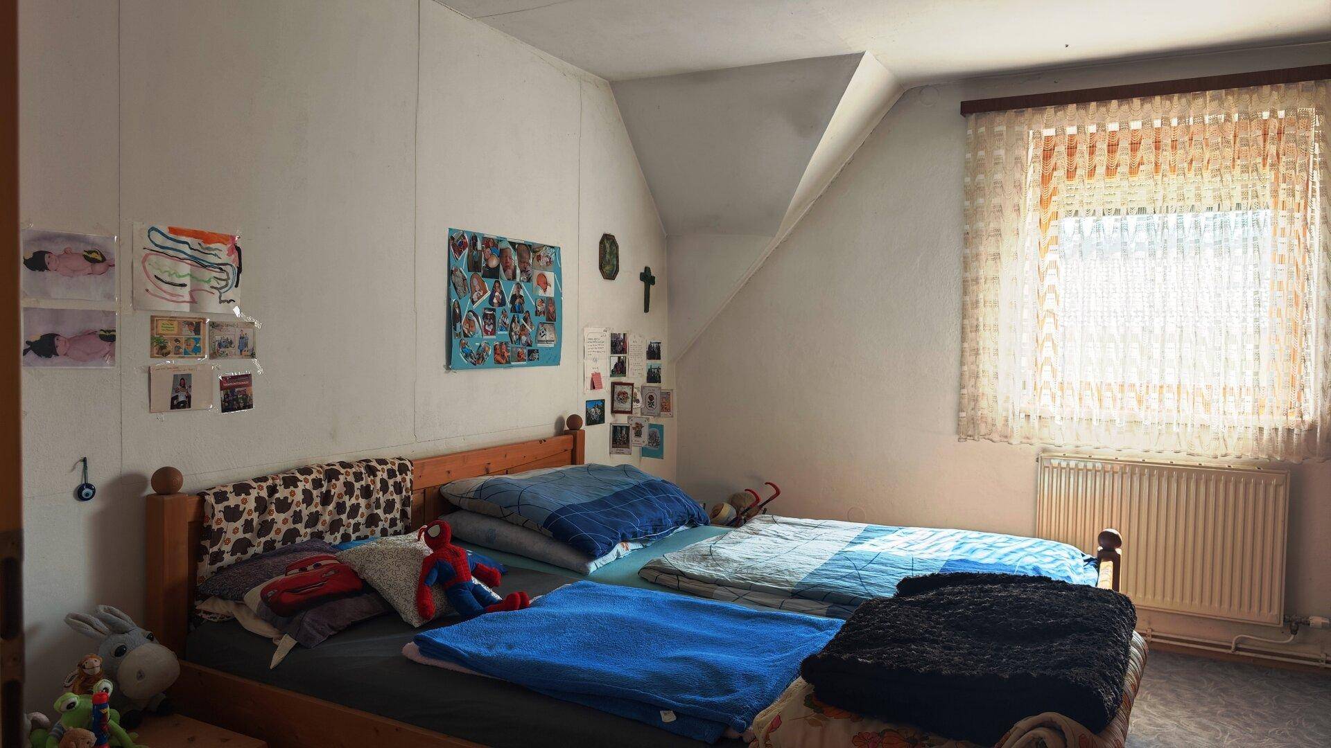 Geräumiges Schlafzimmer im Dachgeschoss mit Holzbett und Blick nach draußen.