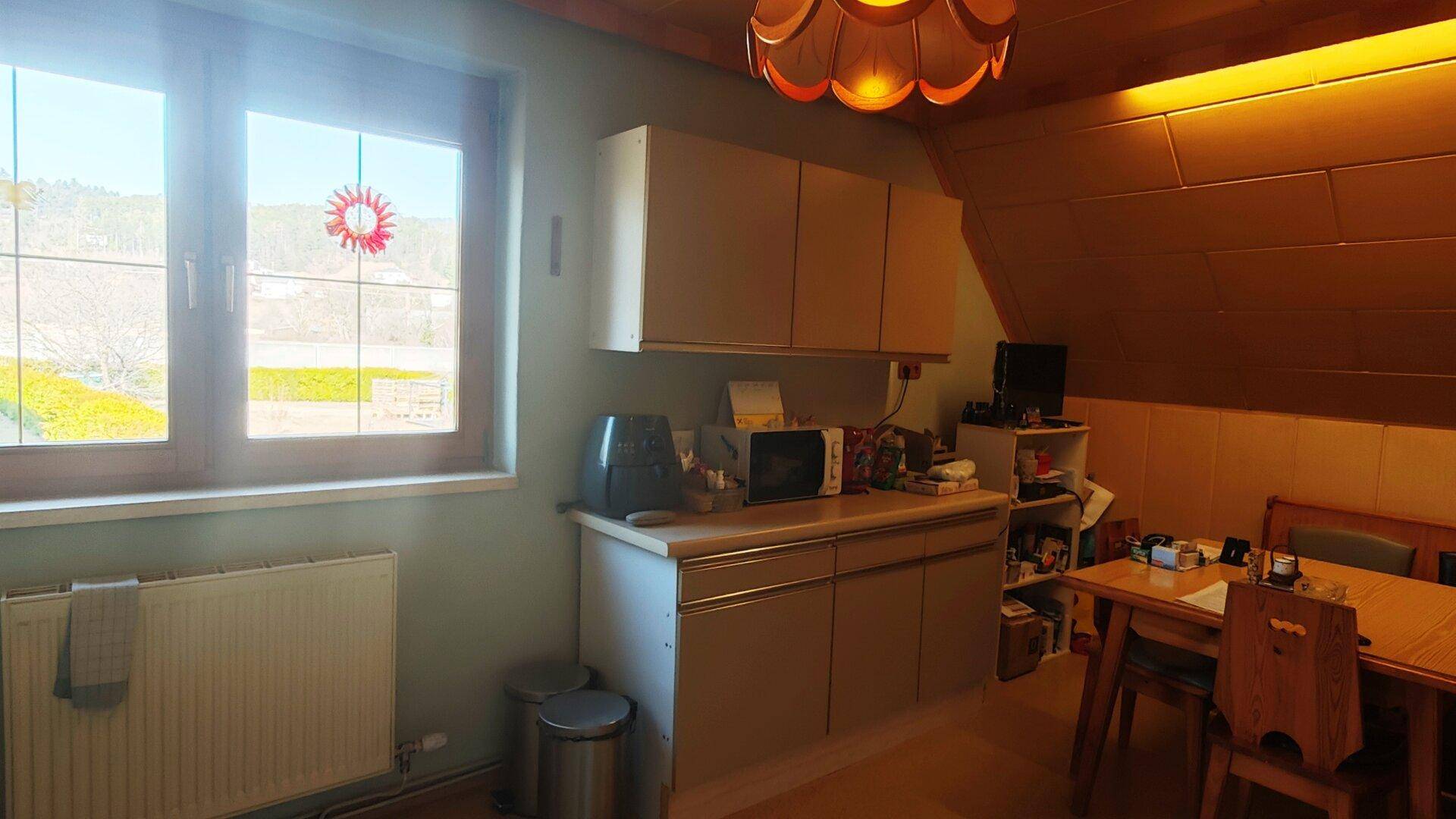 Essbereich in der Küche mit Holztisch, Stühlen und schräger Decke.