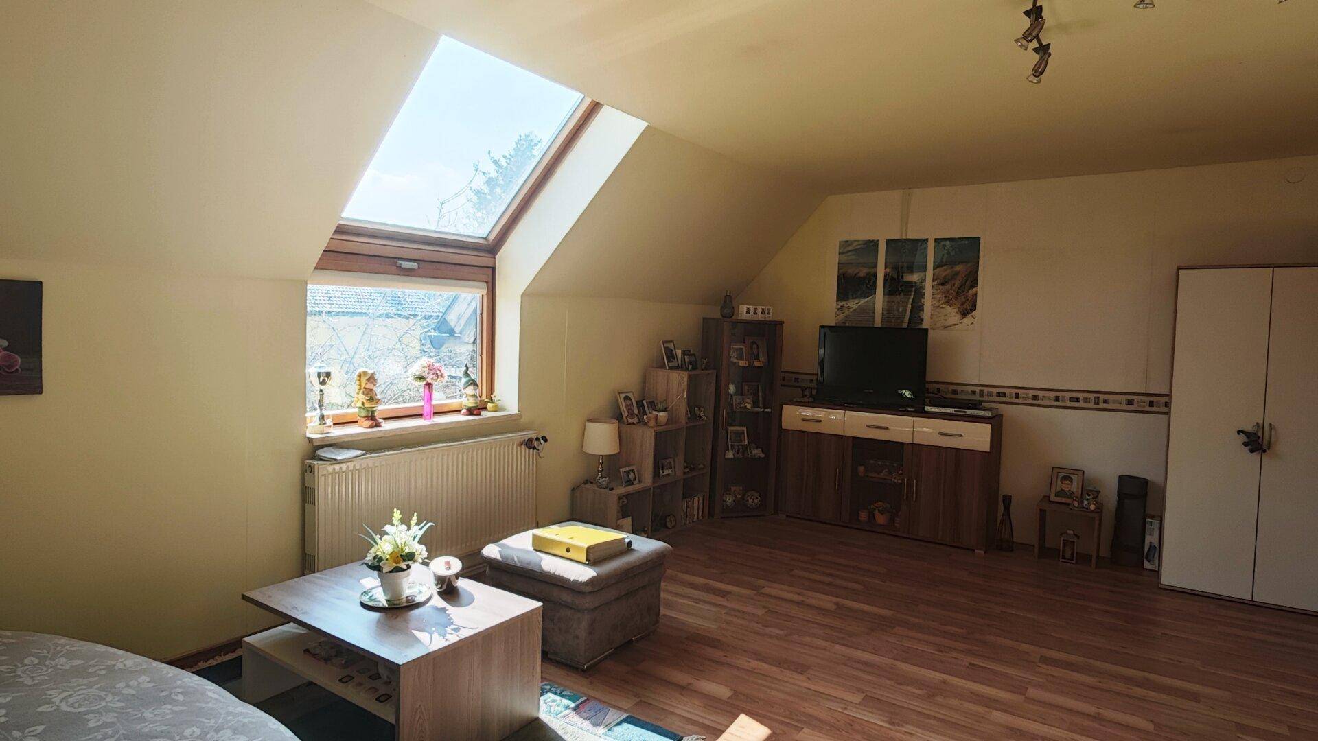 Gemütliches Wohnzimmer mit TV-Möbeln, Regalen und viel Tageslicht.