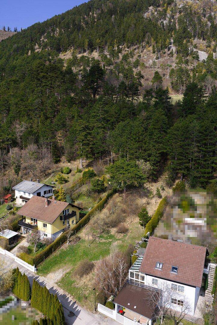 Luftaufnahme von Häusern am bewaldeten Hang mit Blick auf die umliegende Natur.