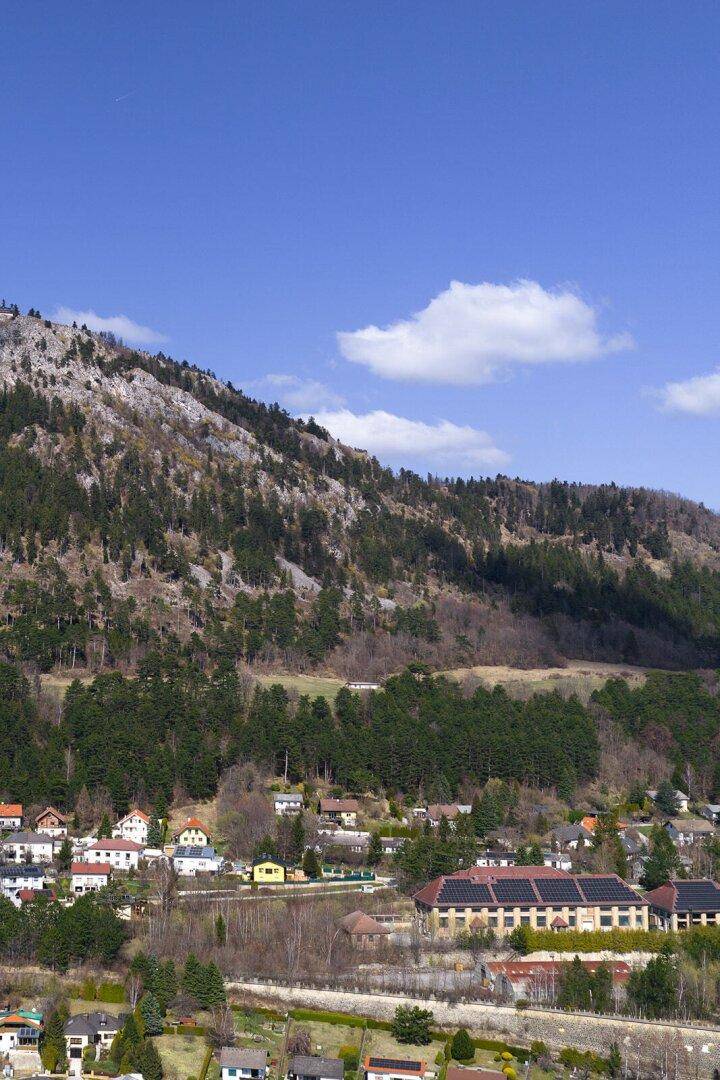 Panoramablick auf ein Dorf am Fuße eines Berges, mit einem Gebäude mit Solaranlagen.