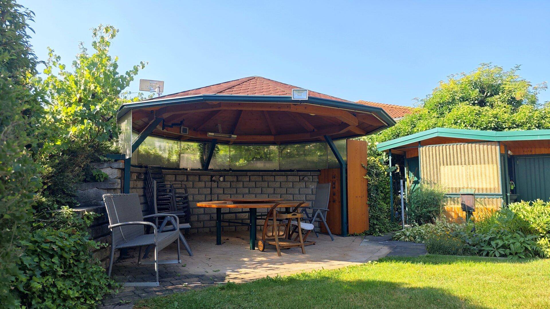 Gemütlicher Gartenpavillon mit Holzdach und Sitzgelegenheiten, ideal für entspannte Stunden im Freien.