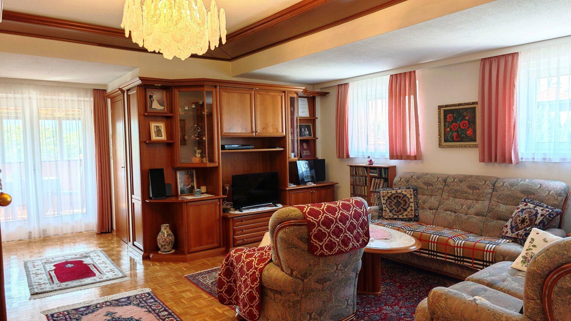 Helles Wohnzimmer mit bequemen Sofas, Holzmöbeln und großen Fenstern, die viel Licht hereinlassen.