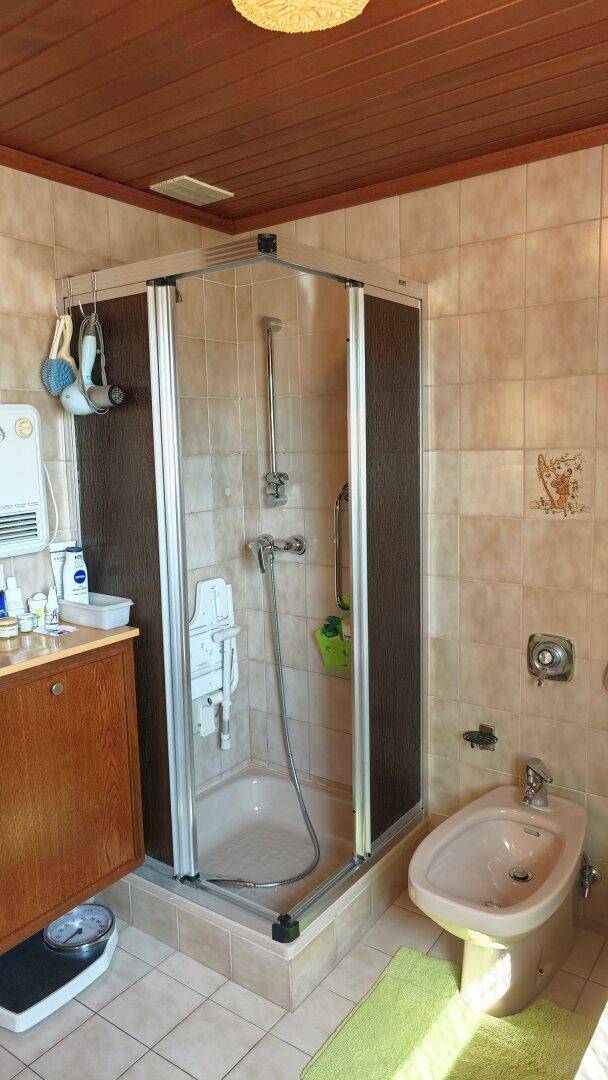 Badezimmer mit Duschkabine, Bidet und gefliesten Wänden in warmen, beigen Farbtönen.