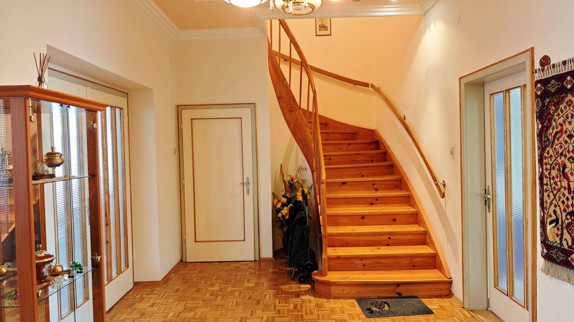 Geräumiger Flur mit eleganter Holztreppe und Parkettboden, der die verschiedenen Etagen verbindet.