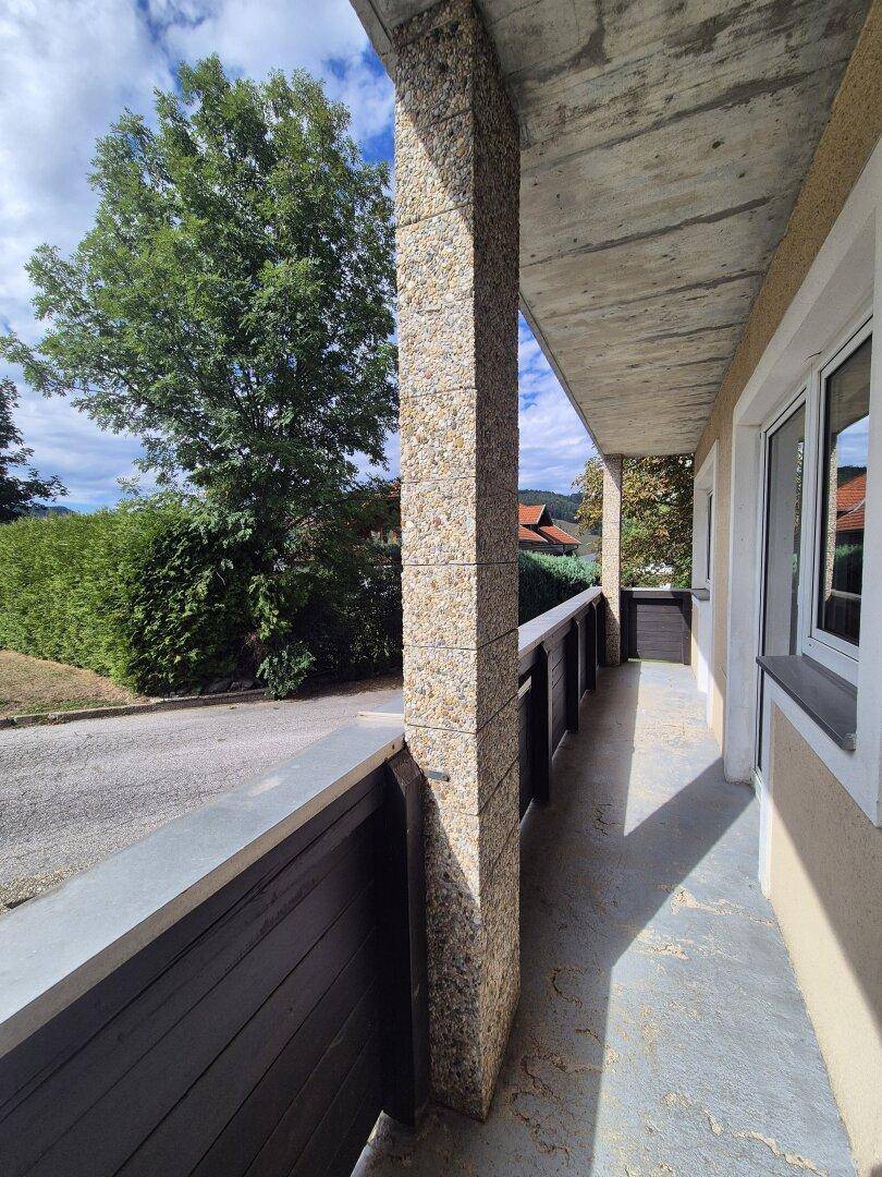 Langer Balkon mit Steinsäule und Blick auf die grüne Umgebung, ideal für Entspannung im Freien.